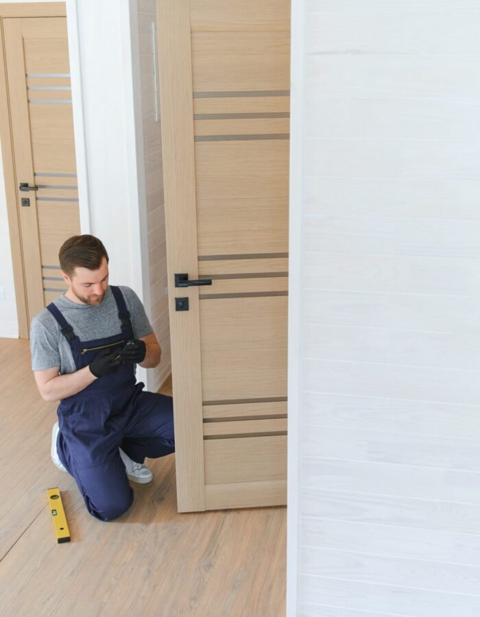 A handsome male worker is installing a new door in a house