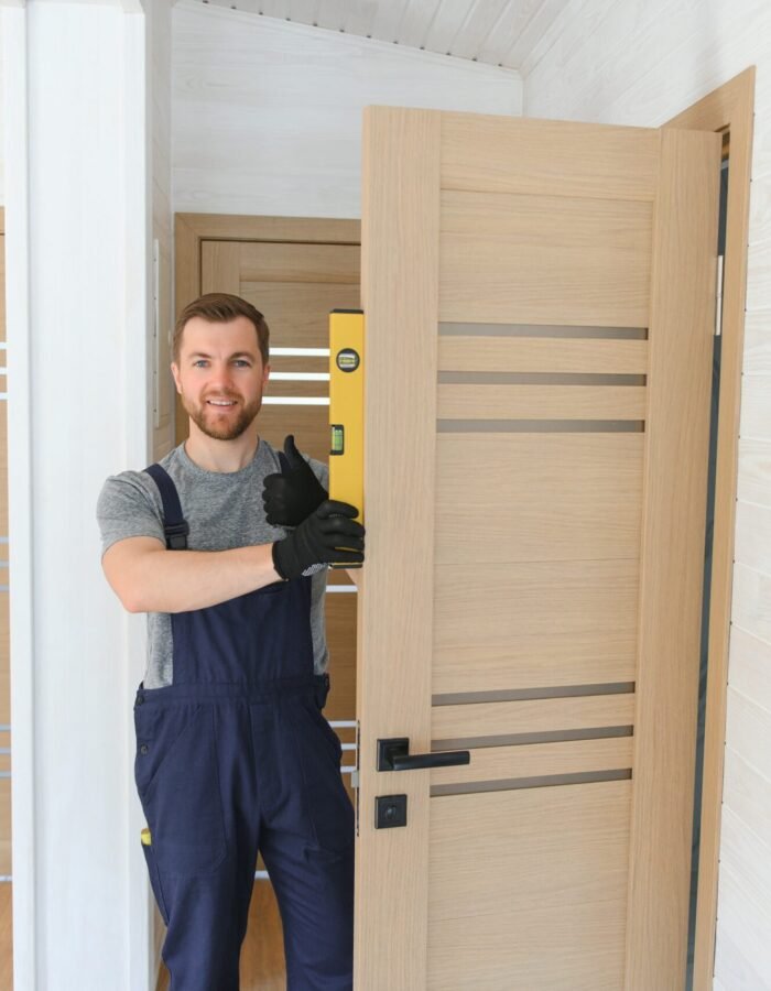 A handsome male worker is installing a new door in a house