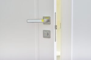 Close up of modern chromed metal door handle on a white interior door.
