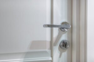 Modern metal door handle on white wooden door in interior. Knob close-up elements. Door handle, fittings for interior design