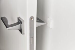 Silver door handle on white door.  Furniture accesories, interior element