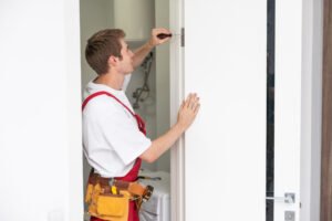 Young man fixing the door in house.